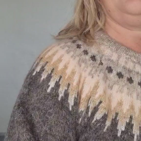 Kvinde i grå strik med mønster i beige og lyse nuancer