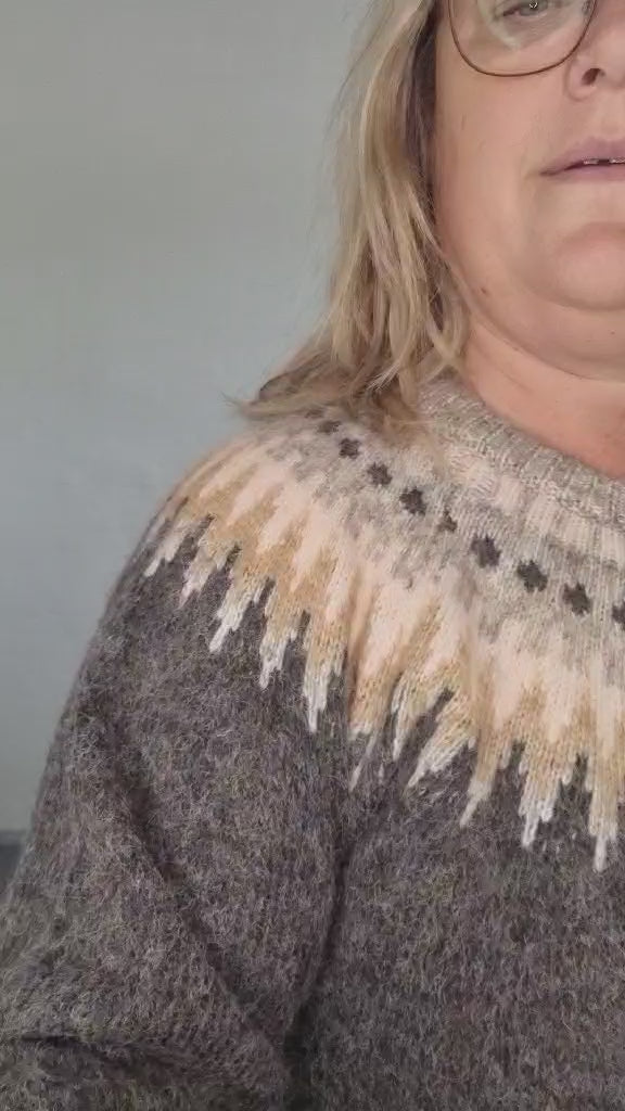 Kvinde i grå strik med mønster i beige og lyse nuancer